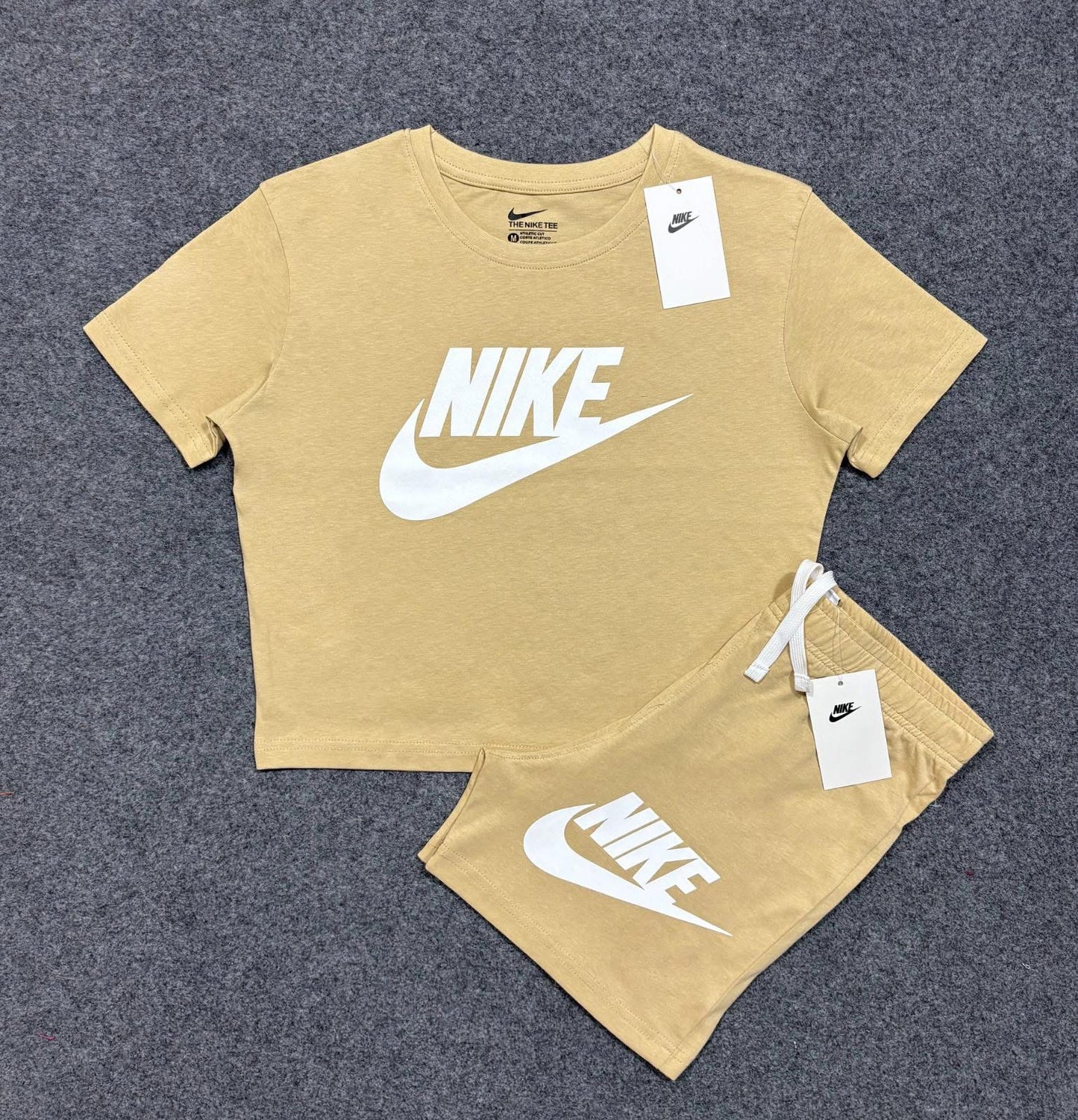 Women's cropped shorts set featuring a short-sleeved top and matching shorts with Nike logo in beige color.