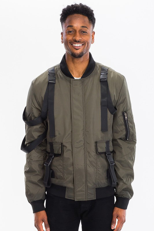 Man wearing a tactical utility bomber jacket with straps and buckles in olive green color.