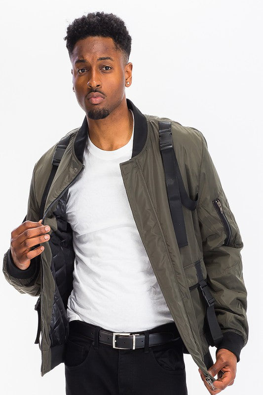 Model wearing a tactical utility bomber jacket featuring straps and buckles, showcasing the functional design.
