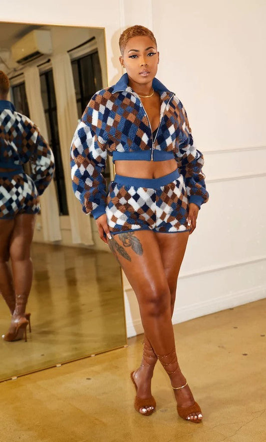 Model wearing a checker print two piece set featuring a zip-up jacket and matching shorts, showcasing a chic style.