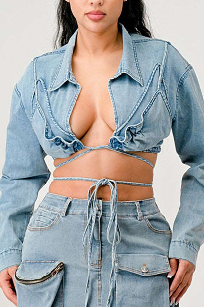 Confident woman wearing a cropped denim jacket with tie-front, showcasing stylish details and a playful vibe.