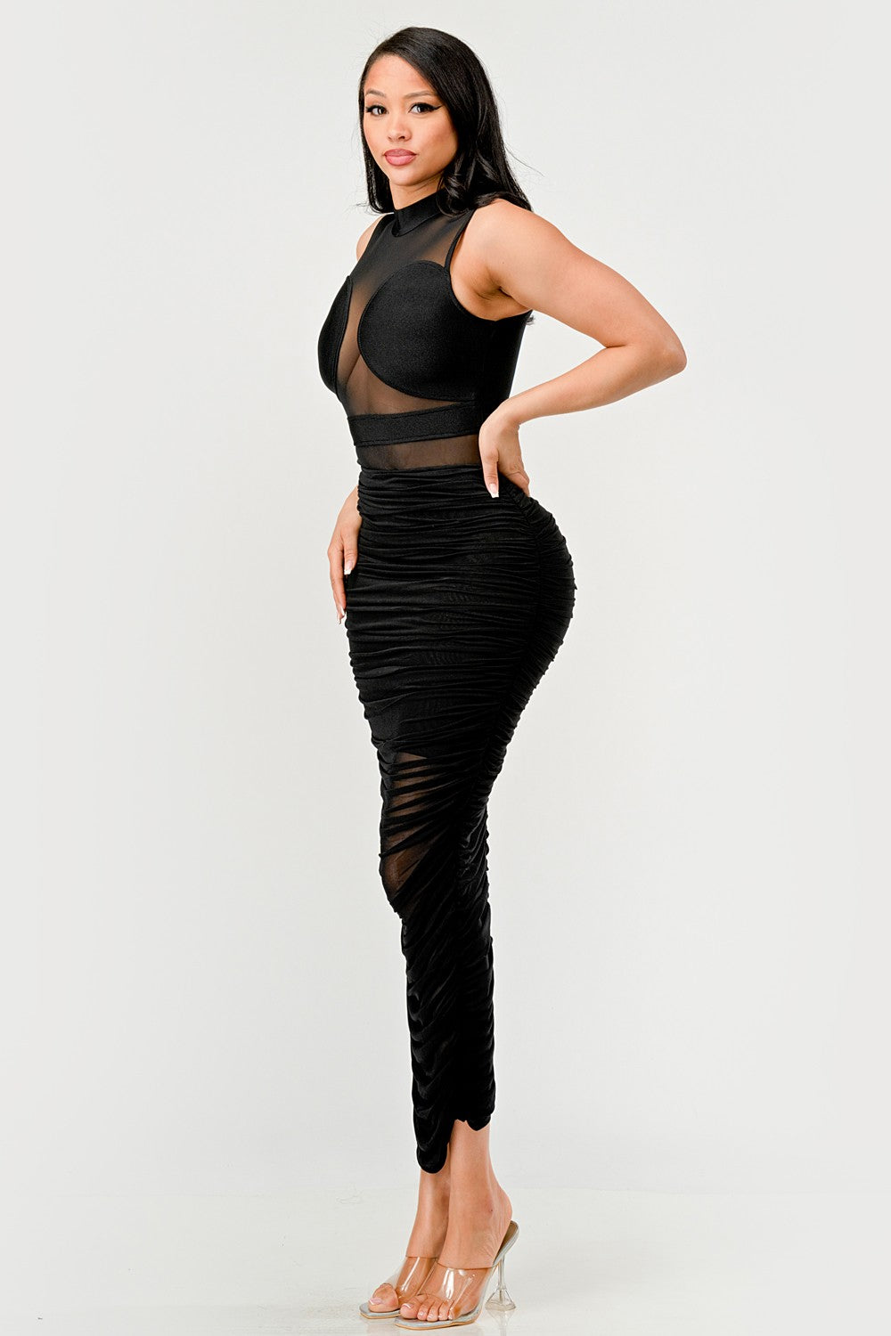 Model showcasing a sleek black sheer illusion midi dress featuring a high-neck top and ruched skirt.