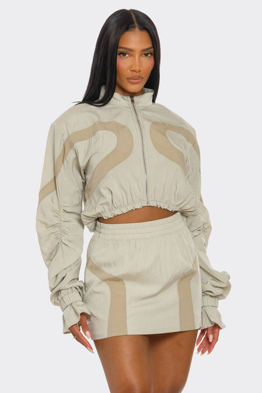Two-tone windbreaker skirt set featuring a cropped jacket and high-rise mini skirt.