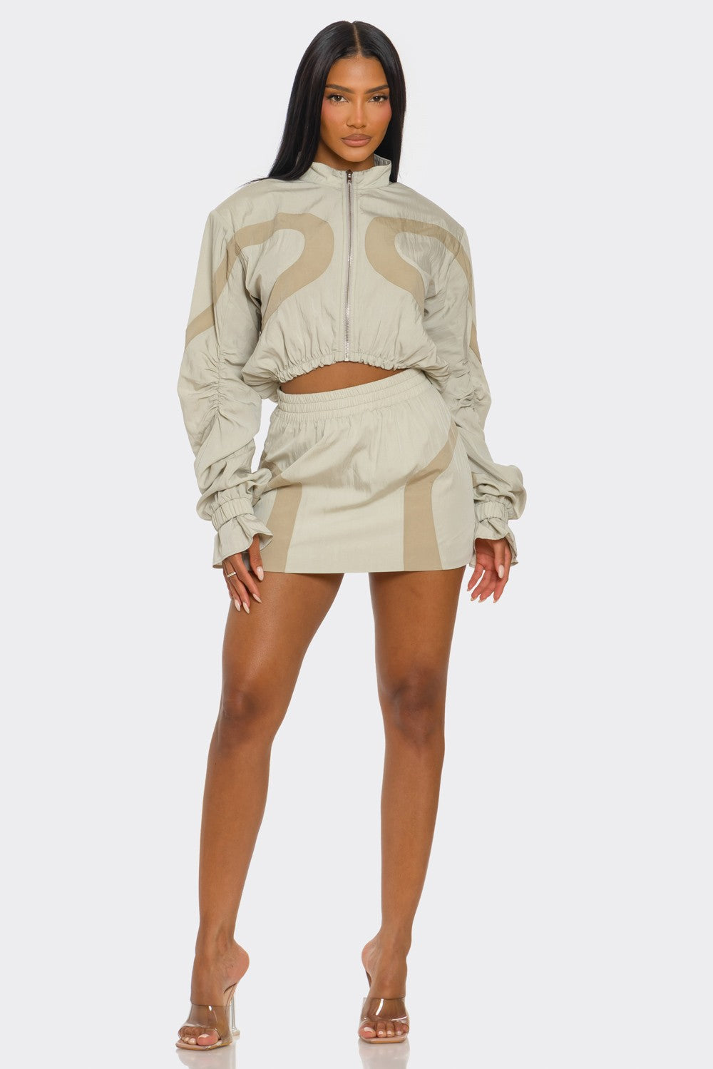 Model wearing a two-tone windbreaker skirt set featuring a cropped jacket and high-rise mini skirt.