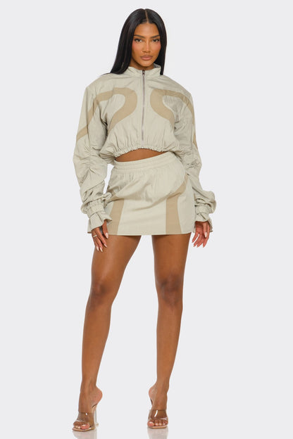 Model wearing a two-tone windbreaker skirt set featuring a cropped jacket and high-rise mini skirt.