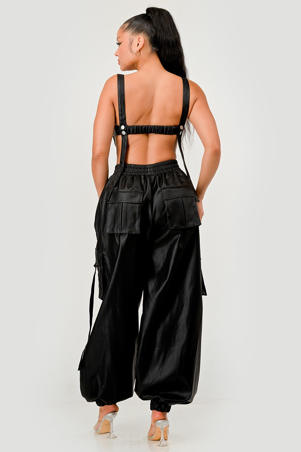 Back view of a model wearing a black utility crop top cargo pants set featuring utility details and adjustable straps.