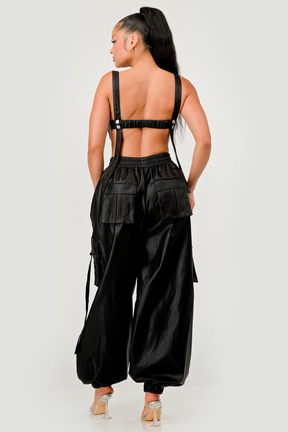 Back view of a model wearing a black utility crop top cargo pants set featuring utility details and adjustable straps.
