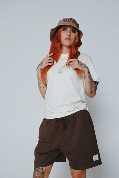 Young woman wearing a graphic statement bucket hat, casual t-shirt, and shorts, showcasing streetwear fashion.