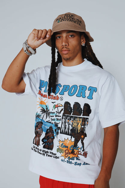 A young man wearing a graphic statement bucket hat and a colorful t-shirt with beach club design, showcasing bold streetwear style.