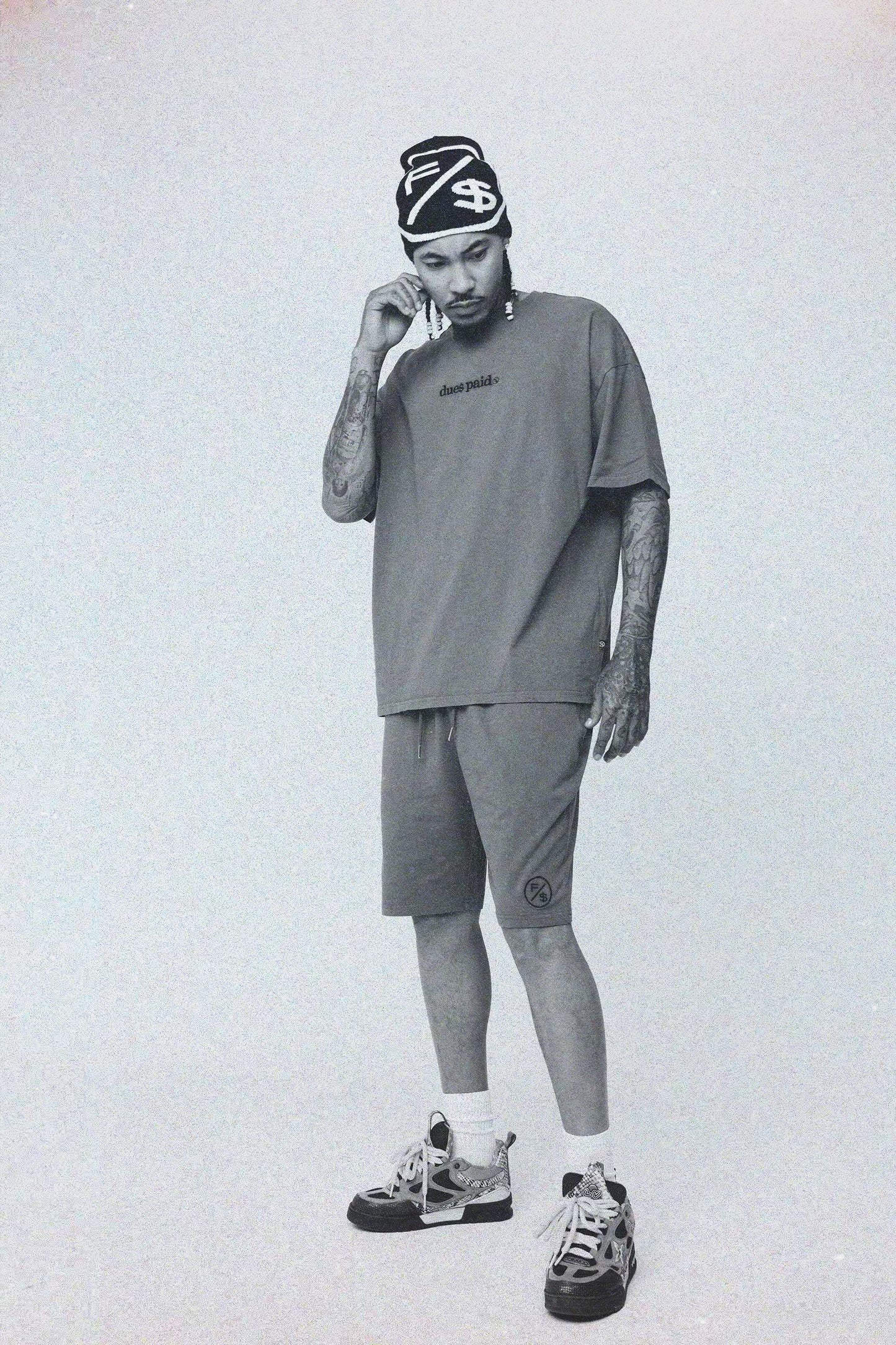 Man wearing oversized graphic t-shirt streetwear with matching shorts and beanie, showcasing relaxed street style.