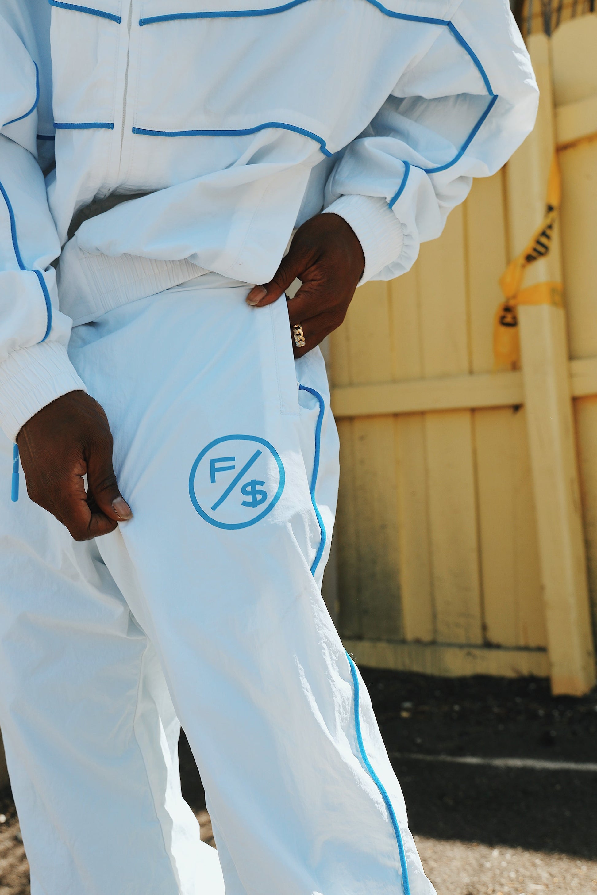 Person wearing lightweight utility track pants with logo detail in a stylish streetwear setting.