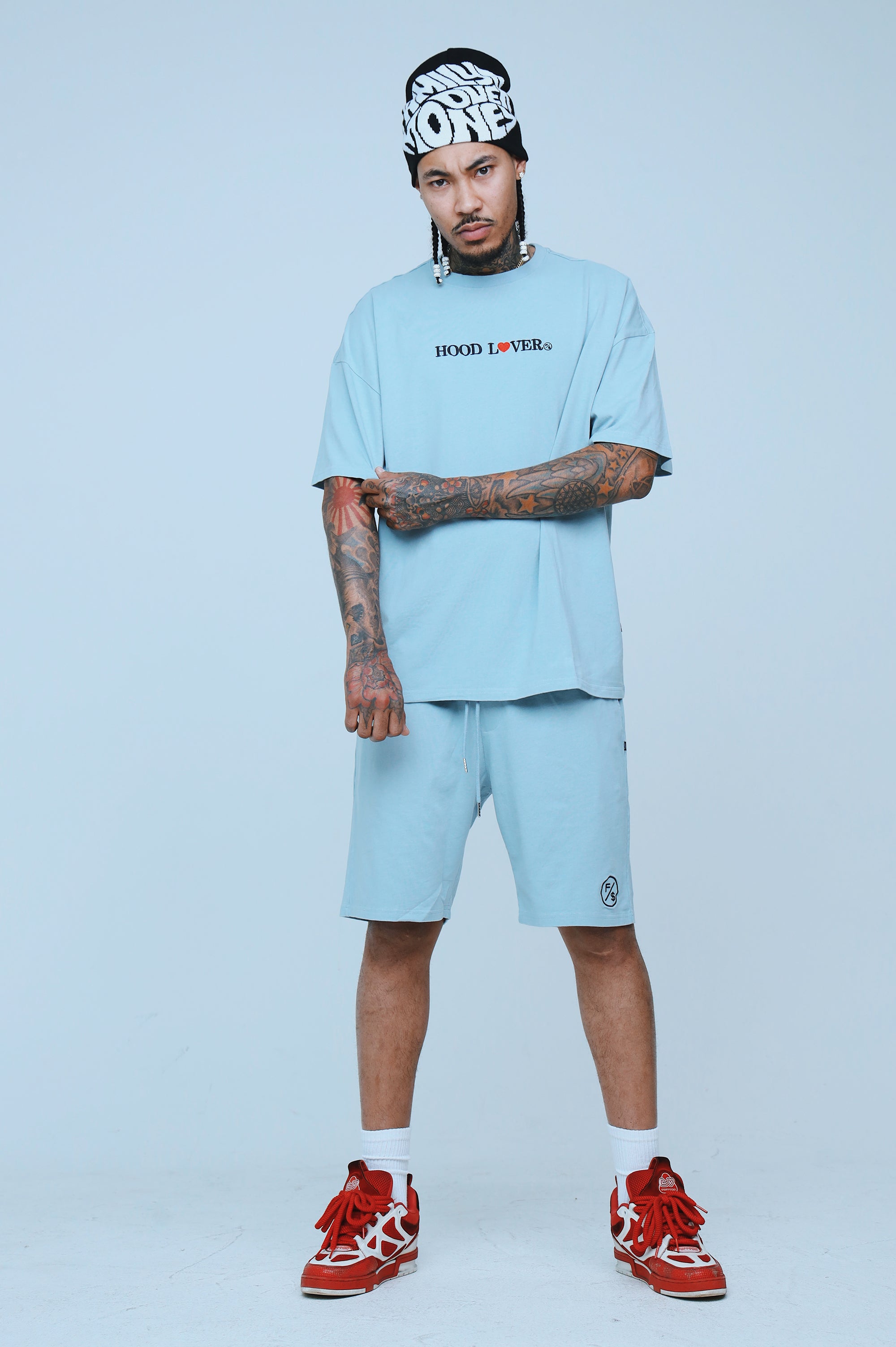 Model wearing an oversized graphic streetwear t-shirt with relaxed fit in light blue, paired with matching shorts.