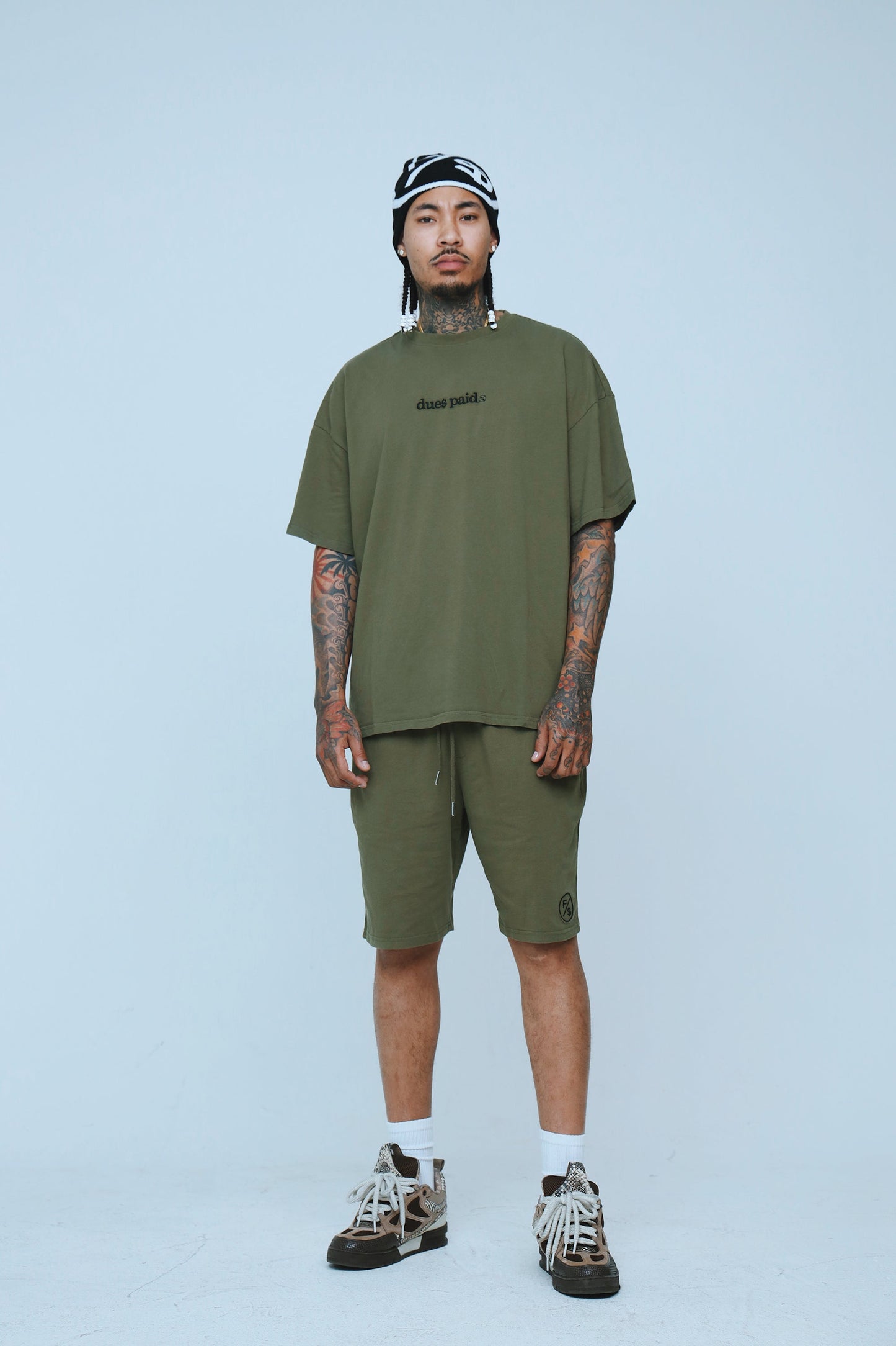 Model wearing oversized streetwear shorts and matching oversized tee in olive green, showcasing relaxed streetwear style.