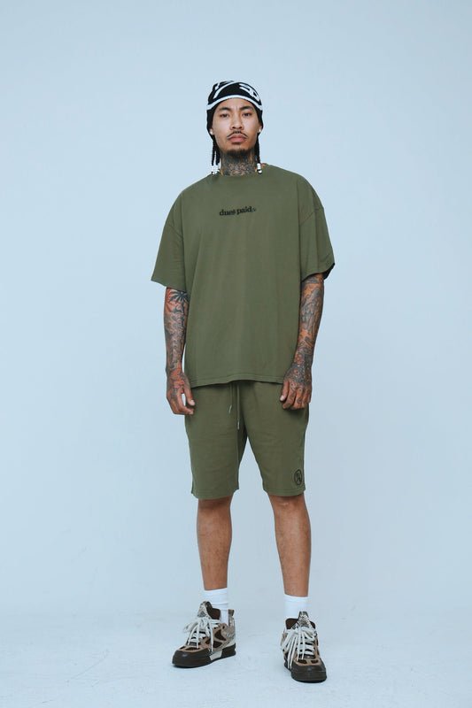 Model wearing oversized streetwear shorts and matching oversized tee in olive green, showcasing relaxed streetwear style.
