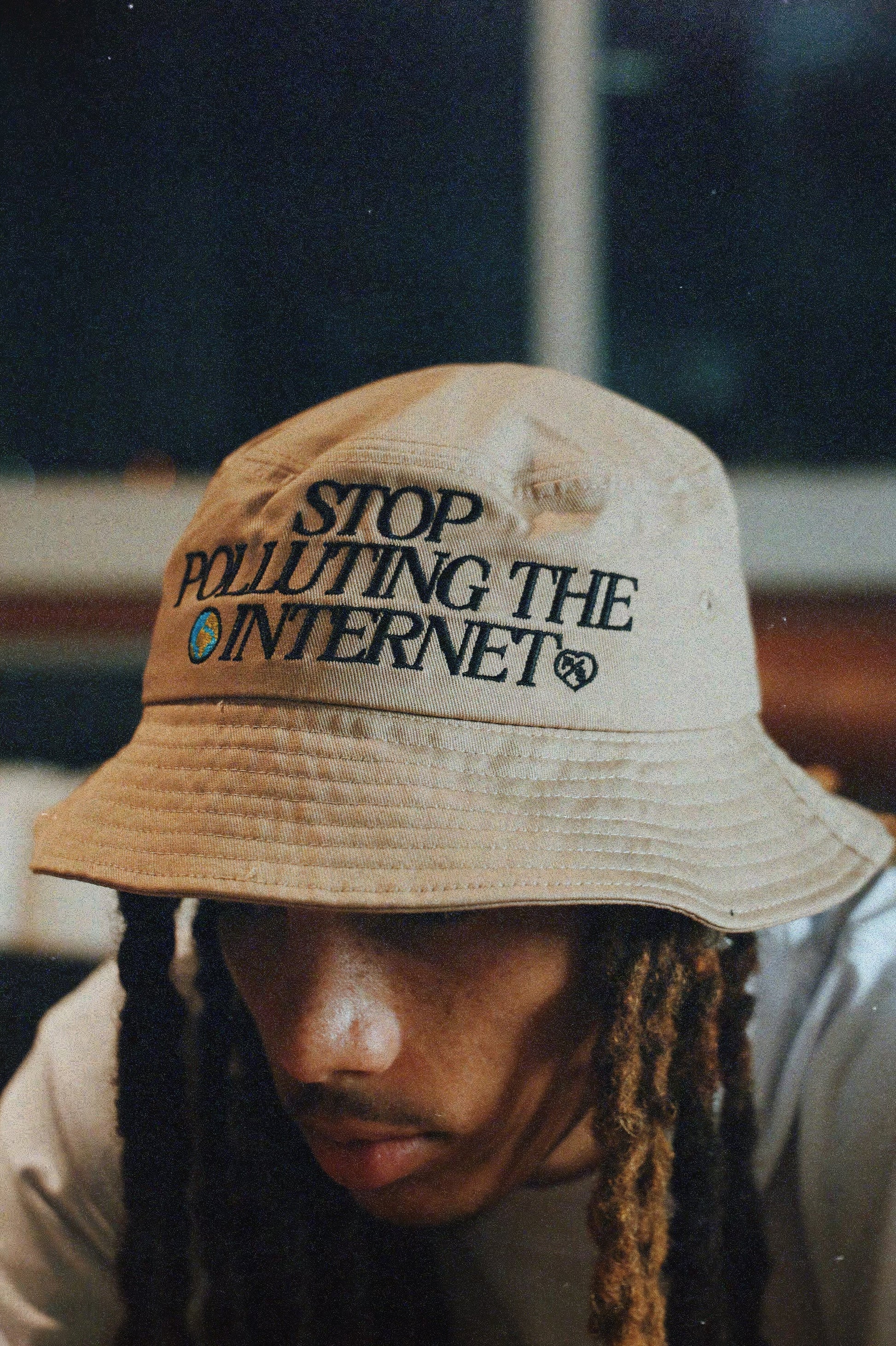 Unisex statement bucket hat with graphic featuring 'Stop Polluting the Internet' design worn by a model.