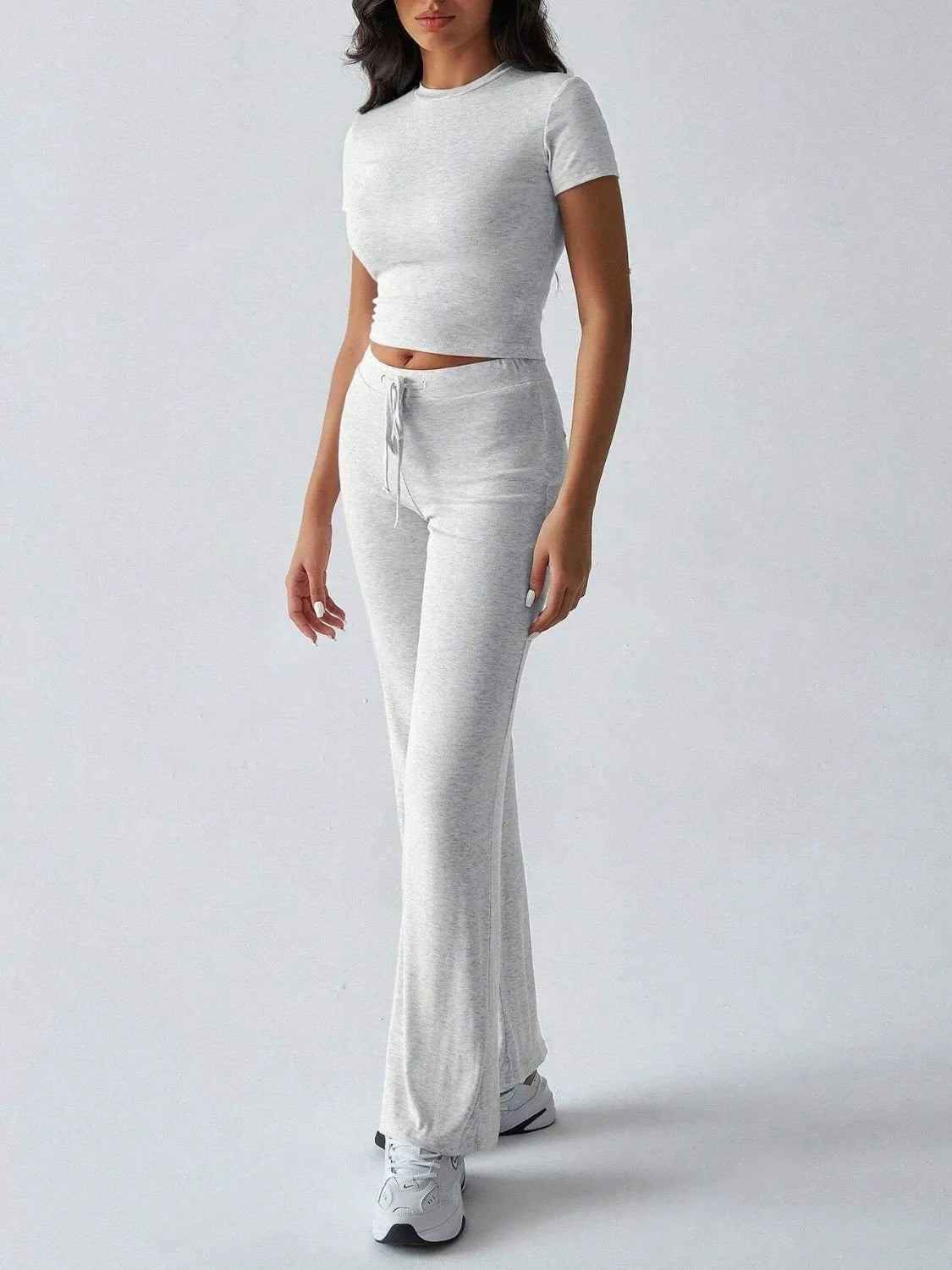 Model wearing a round neck short sleeve top and pants set in light gray, featuring a drawstring for comfort.