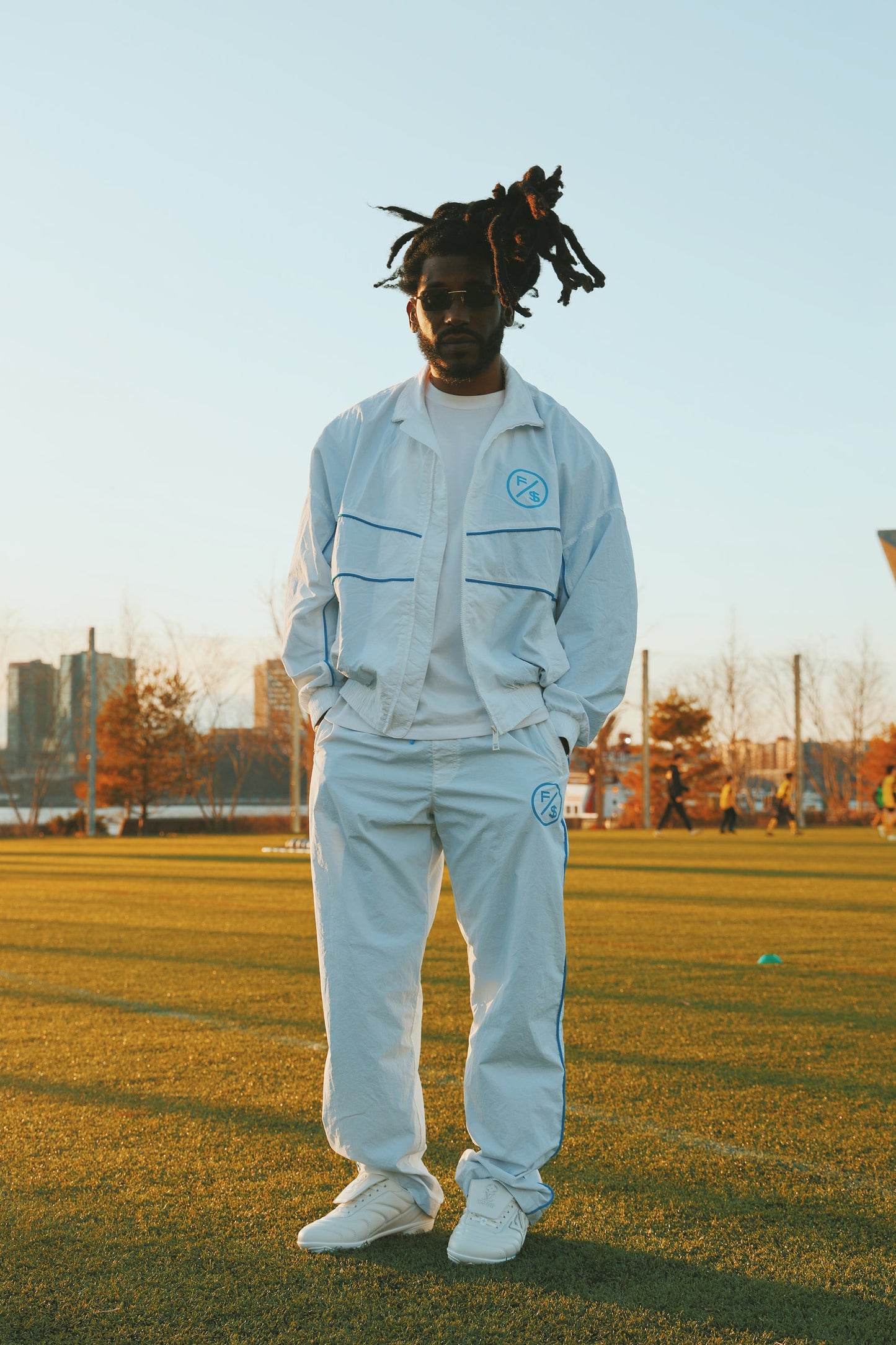Lightweight utility track pants worn by a man in a sporty setting, showcasing a clean streetwear aesthetic.