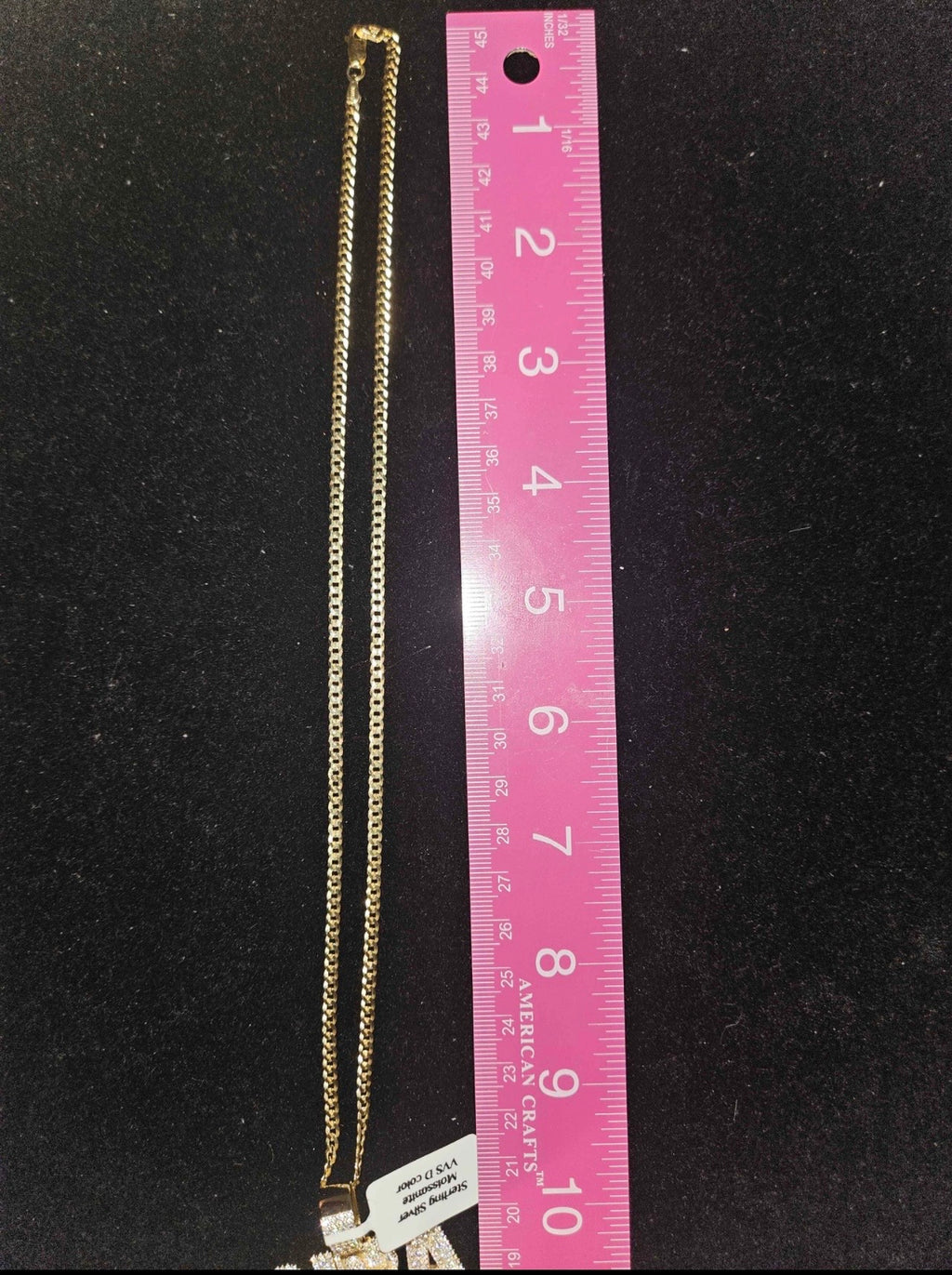 NBA moissanite pendant chain displayed next to a ruler for size reference on a black background.