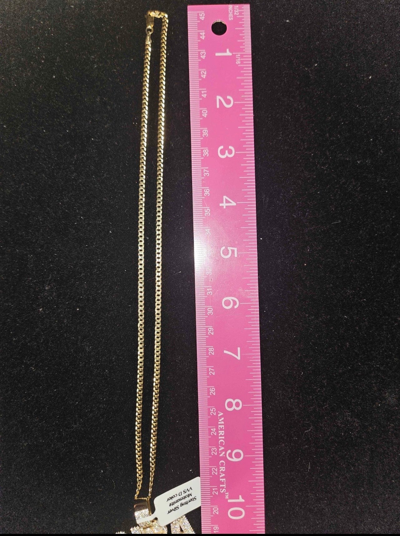 NBA moissanite pendant chain displayed next to a ruler for size reference on a black background.