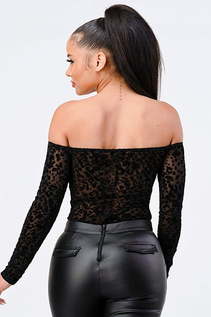Back view of a model wearing a leopard print off shoulder bodysuit with long sleeves and black faux leather pants.