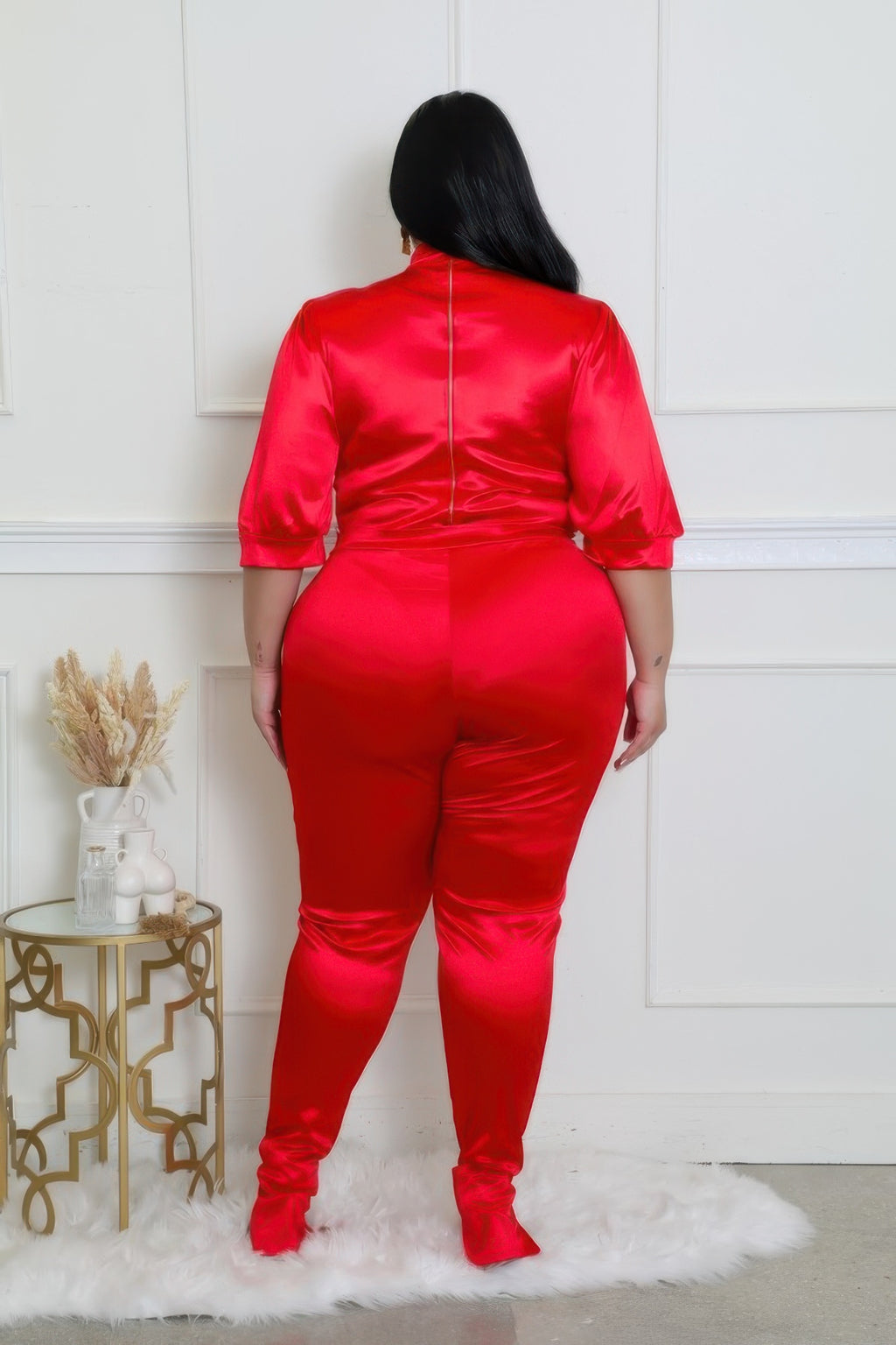 Back view of a curvy model wearing a red bodysuit pants set with a luxurious satin finish.