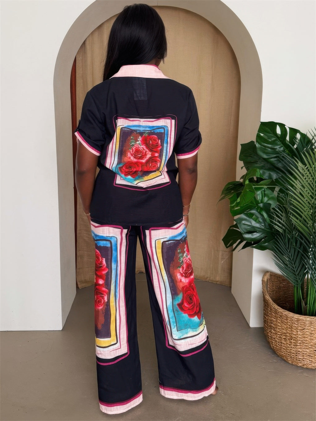 Back view of rose print lounge set featuring black button-up top and wide-leg pants with bold red roses.