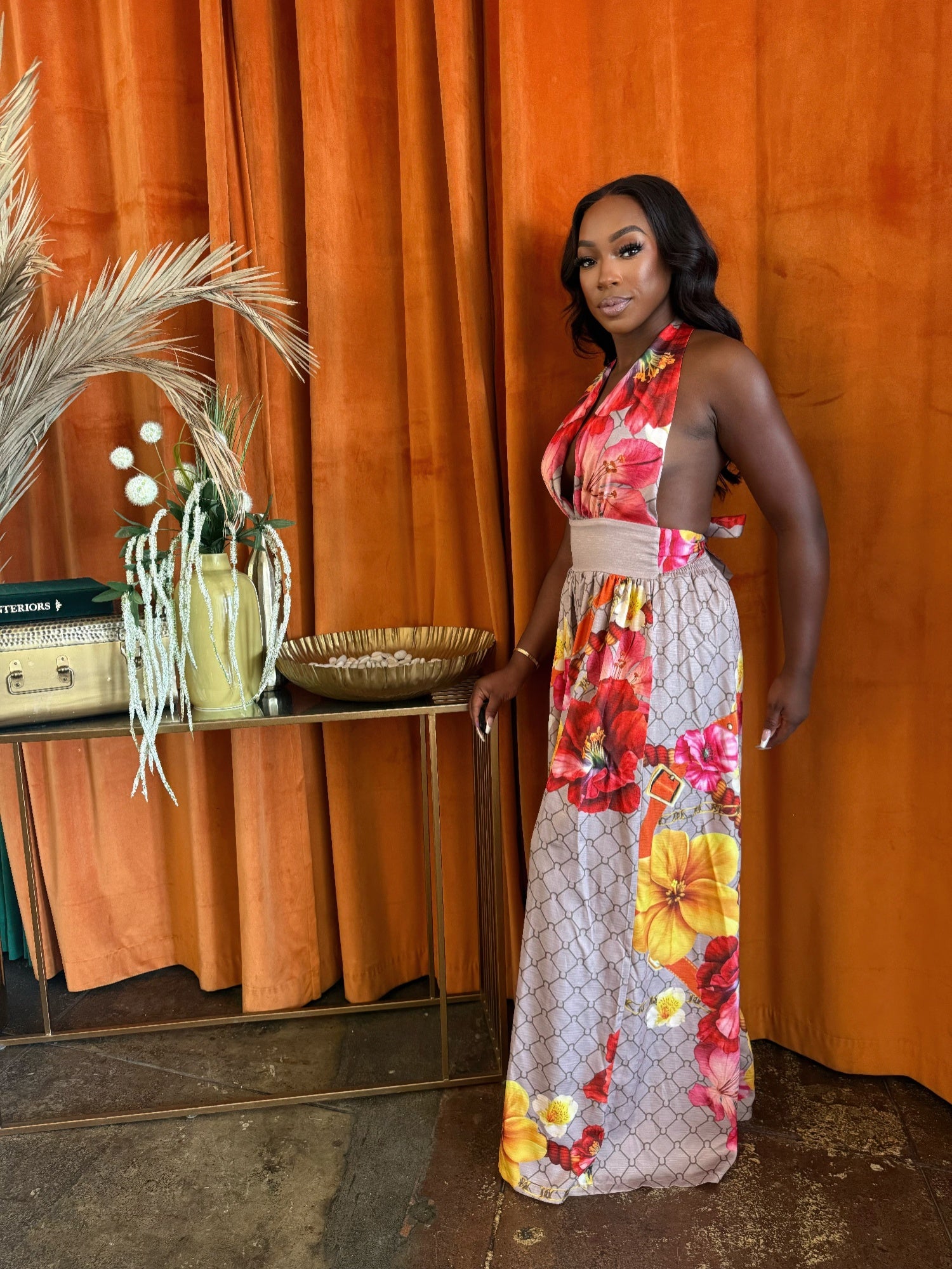 Tropical floral jumpsuit displayed in a chic setting with a stylish model, highlighting vibrant colors and elegant design.