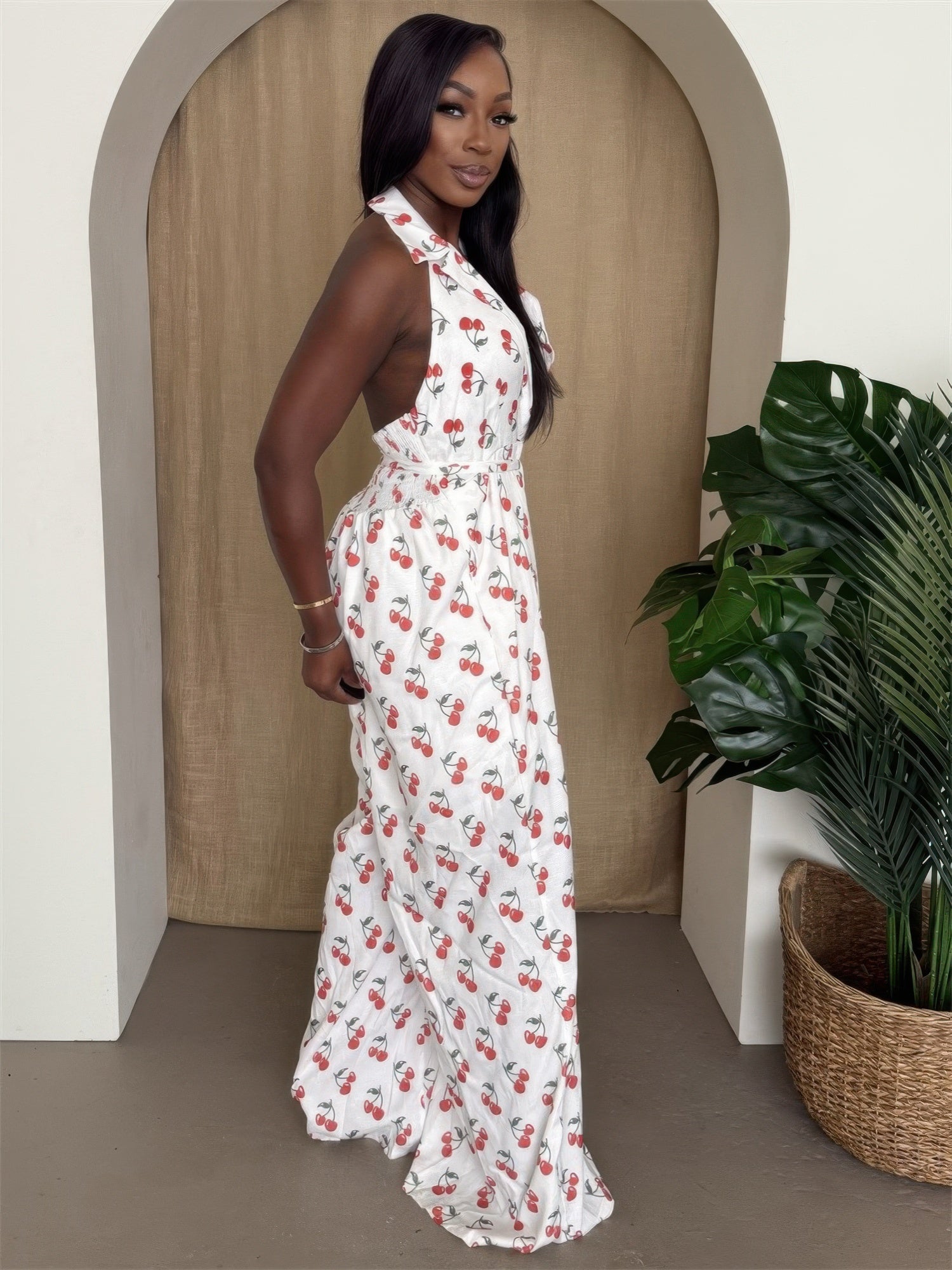 Model wearing a cherry print halter jumpsuit with wide legs, showcasing a vibrant cherry design and elegant silhouette.