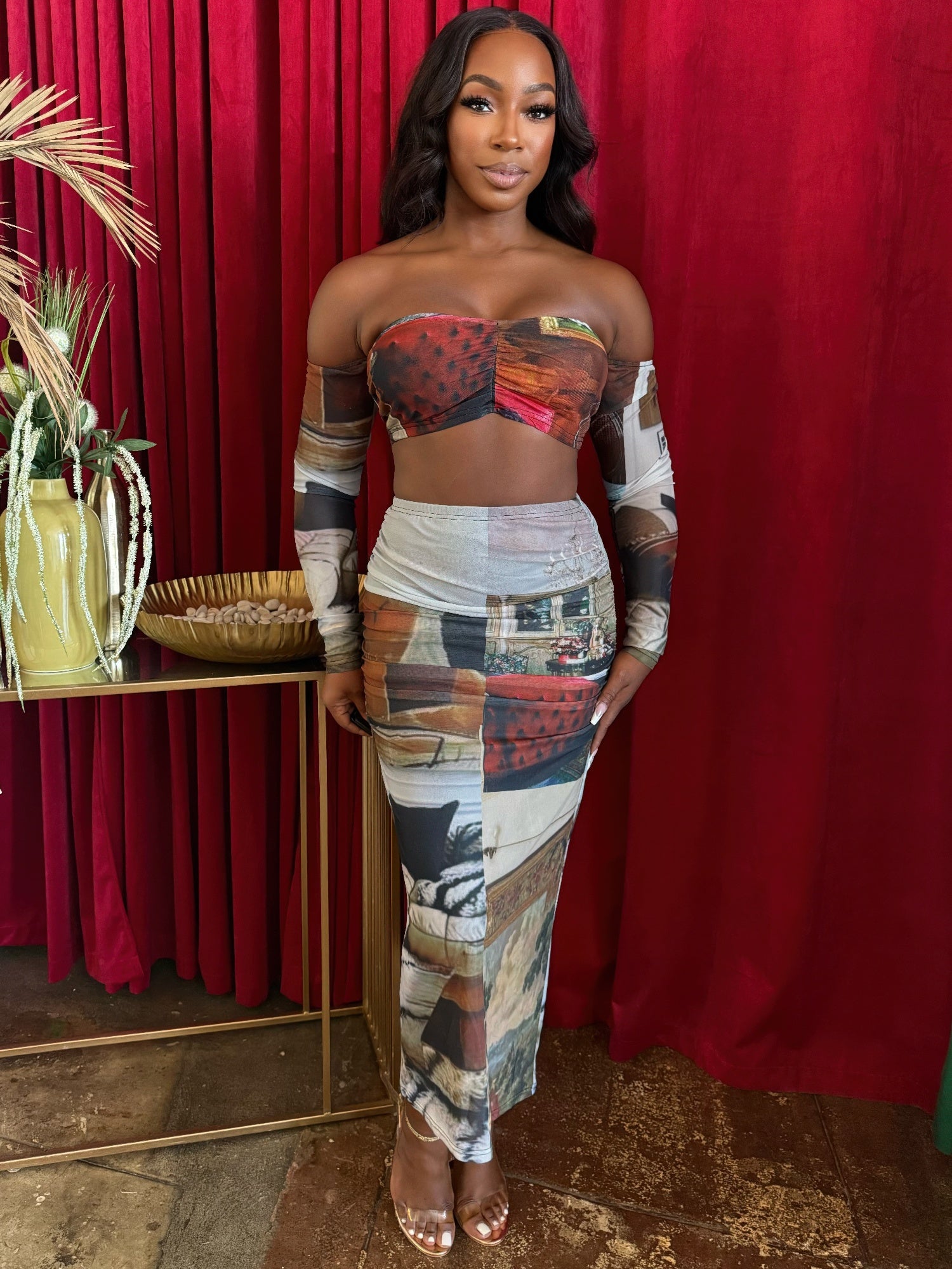 A model showcasing the two-piece skirt set featuring a ruched bandeau top and flowing mesh maxi skirt with artistic patchwork design.