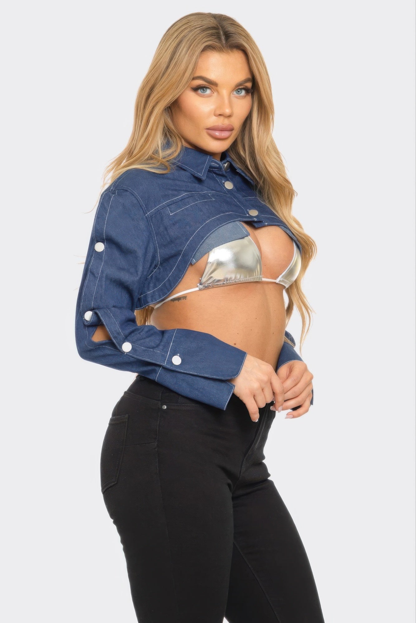 Stylish model wearing a Button Down Denim Bolero jacket over a silver bikini top, paired with black high-waisted jeans.