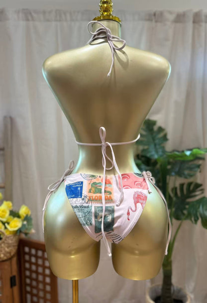 Back view of a model wearing a vintage postcard bikini set featuring a colorful print, perfect for beach outings.