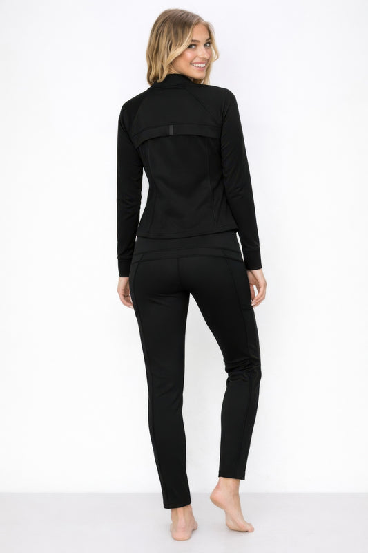 Model wearing an athletic zip up jacket and pant set, showcasing a sleek black design from the back.