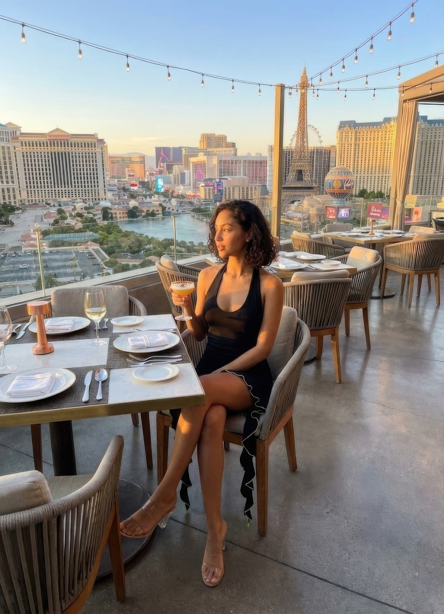 Woman wearing Deep V Neck Ruffle Hem Bodycon Mini Dress seated at rooftop restaurant with Las Vegas Strip skyline at sunset