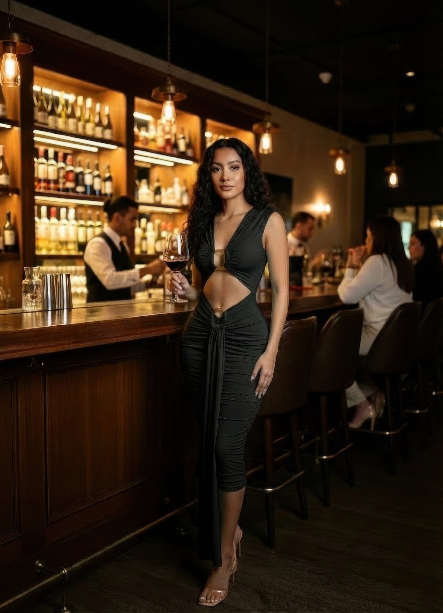 Alt Tag: Cutout Halter Bodycon Midi Dress on model in black stretch jersey with waist cutouts, fitted midi silhouette, posed at bar