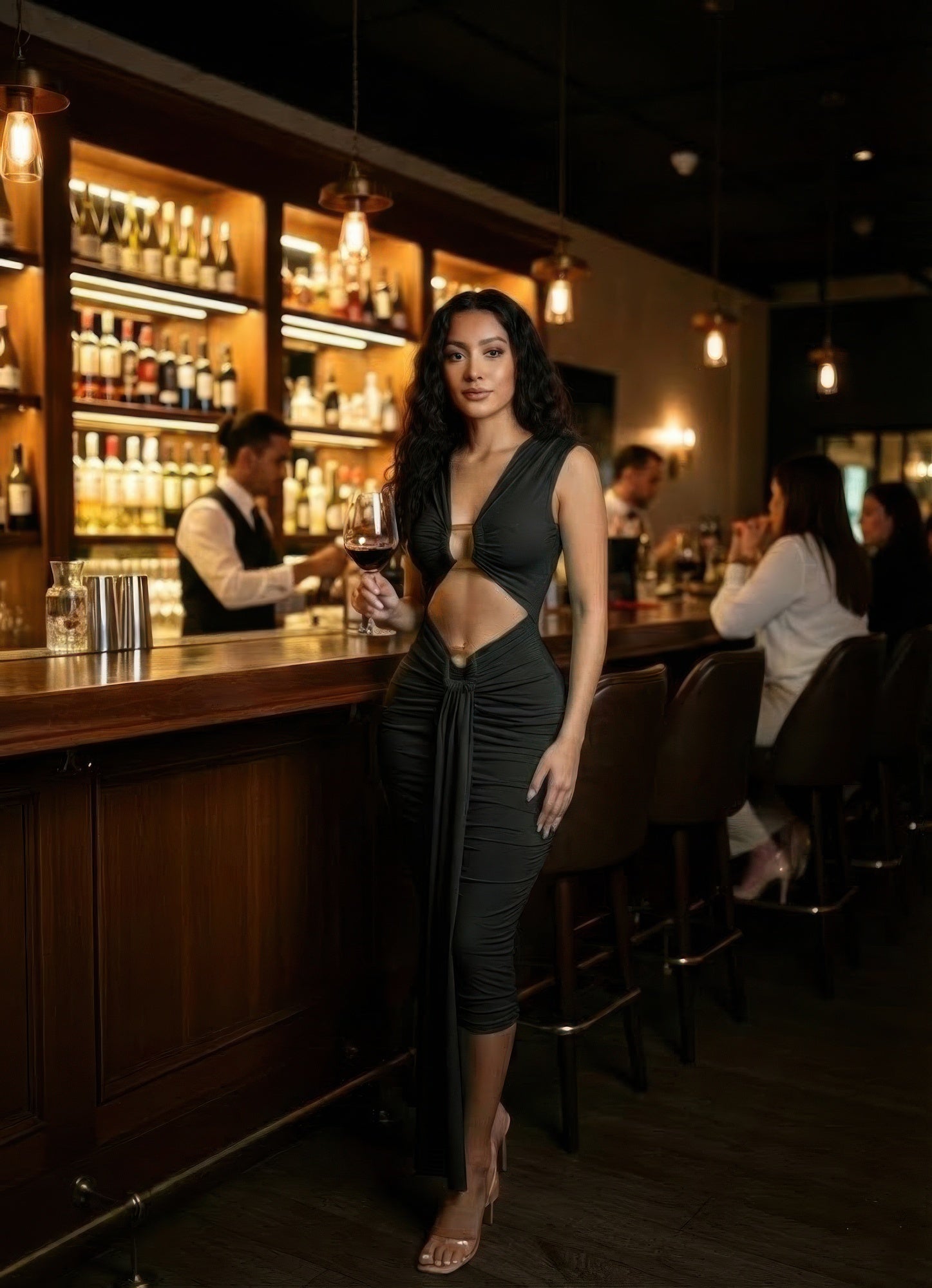 Alt Tag: Cutout Halter Bodycon Midi Dress on model in black stretch jersey with waist cutouts, fitted midi silhouette, posed at bar