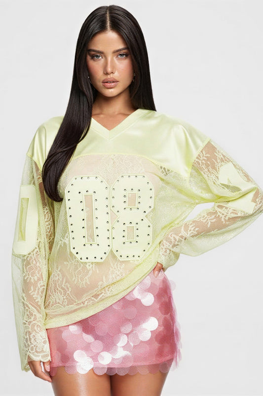 Model wearing a long sleeve jersey top with graphic, featuring a V neckline and rhinestone-accented design.