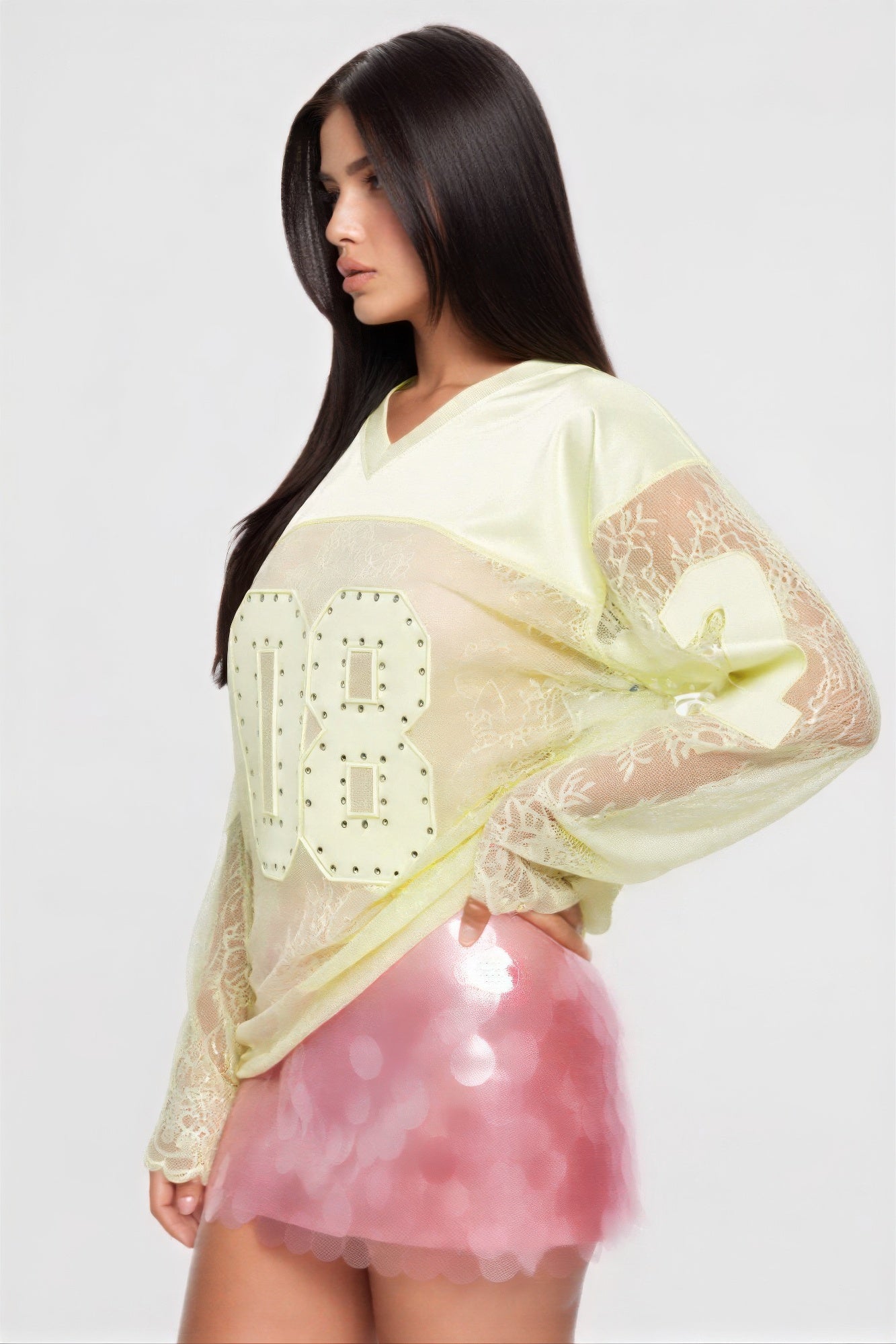Model wearing a long sleeve jersey top with graphic '08', paired with a pink sequined skirt, showcasing a trendy look.