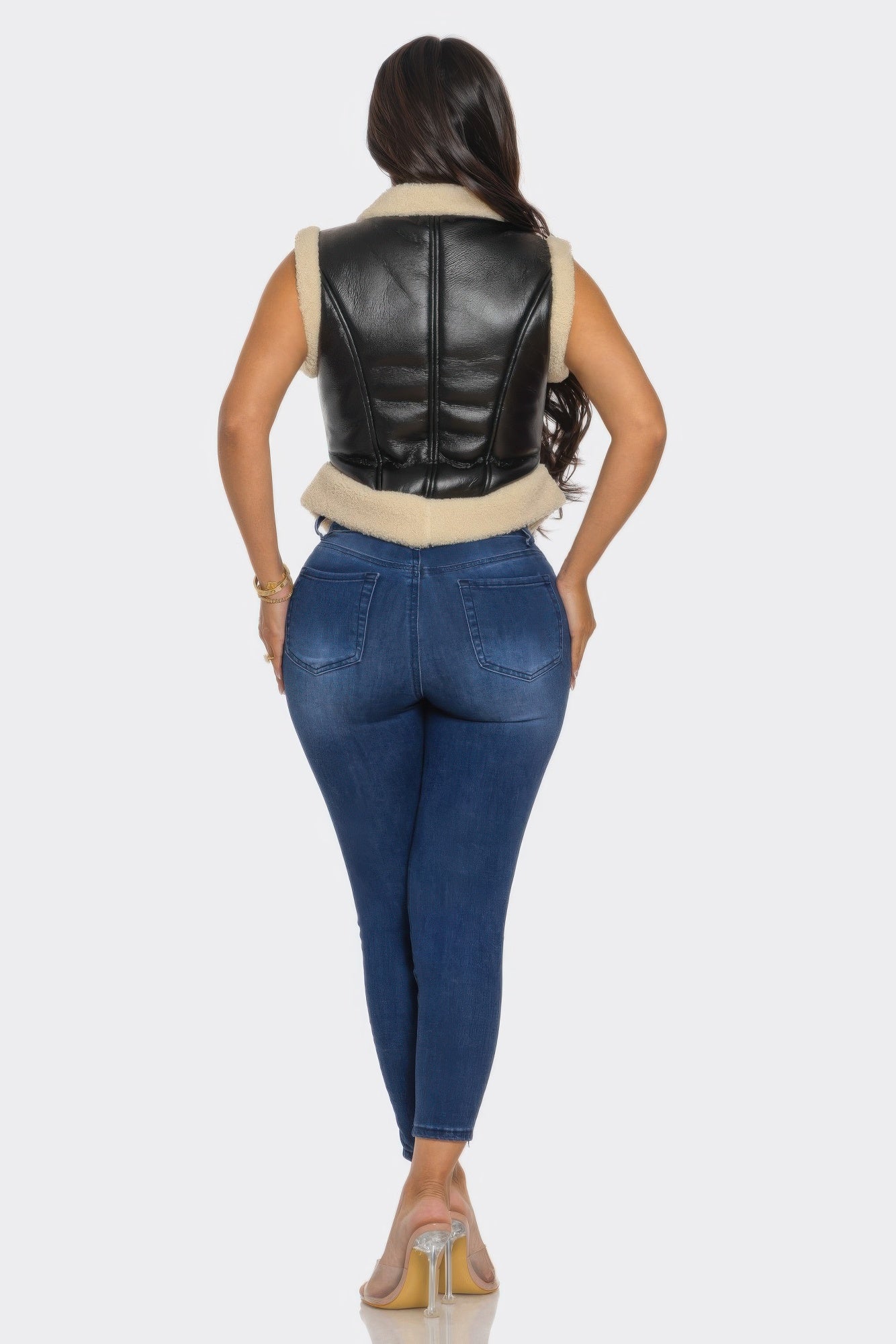 A woman wearing a V trimmed leather vest paired with fitted jeans, showcasing modern style and refined design.