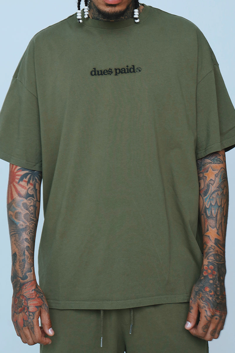 Oversized graphic t-shirt streetwear in olive green with minimal dues paid graphic on front.