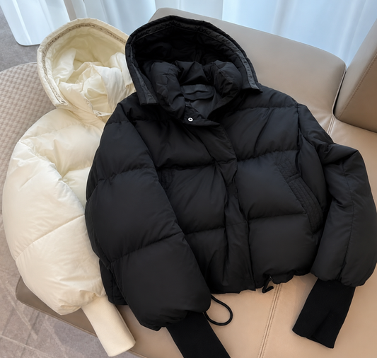Luxury cropped puffer jacket in black and cream, showcasing bold patch detail and a stylish cropped silhouette.
