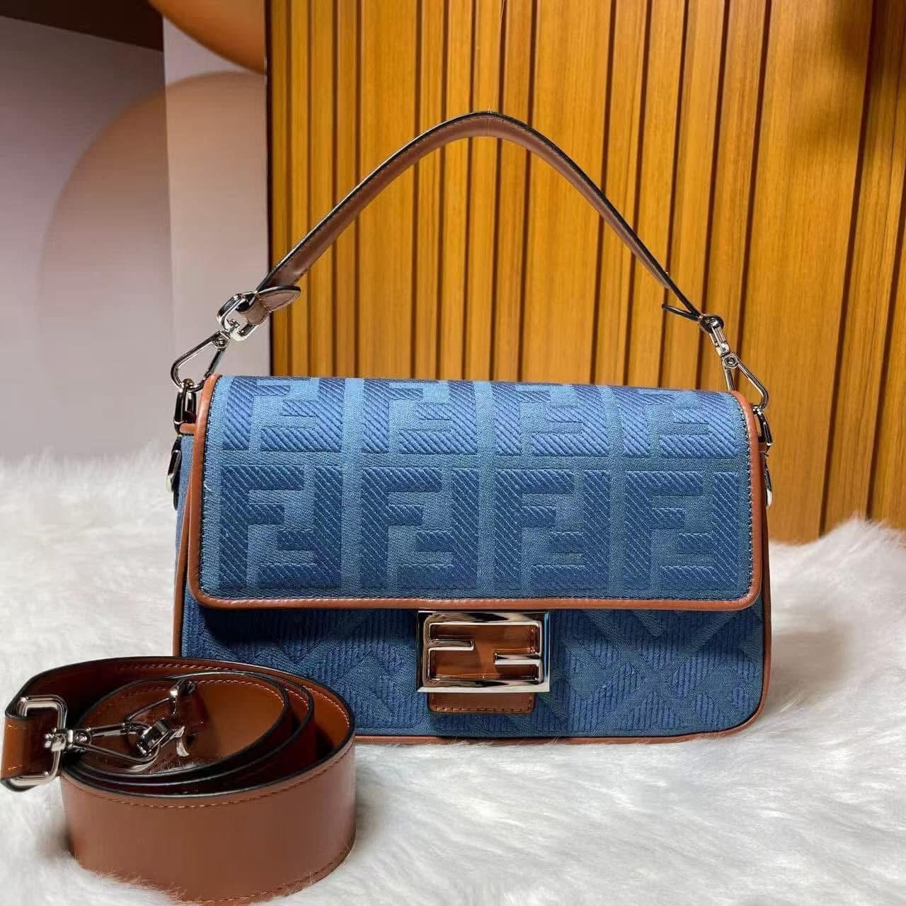 Blue handbag with brown accents and visible brand logo on a white surface.