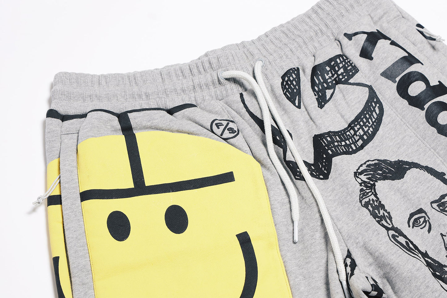 Graphic statement shorts with bold yellow smiley face design and relaxed fit, showcasing streetwear print details.