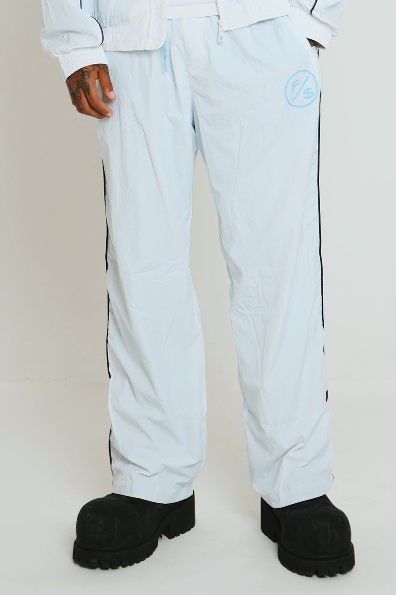 Lightweight utility track pants in light blue, featuring a slight baggy fit and modern streetwear style.