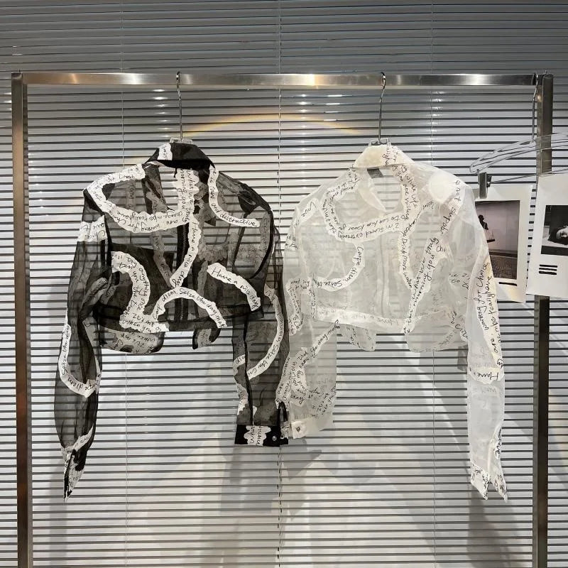 Transparent mesh crop jacket in black and white, featuring unique patterns and a stylish design on a clothing rack.