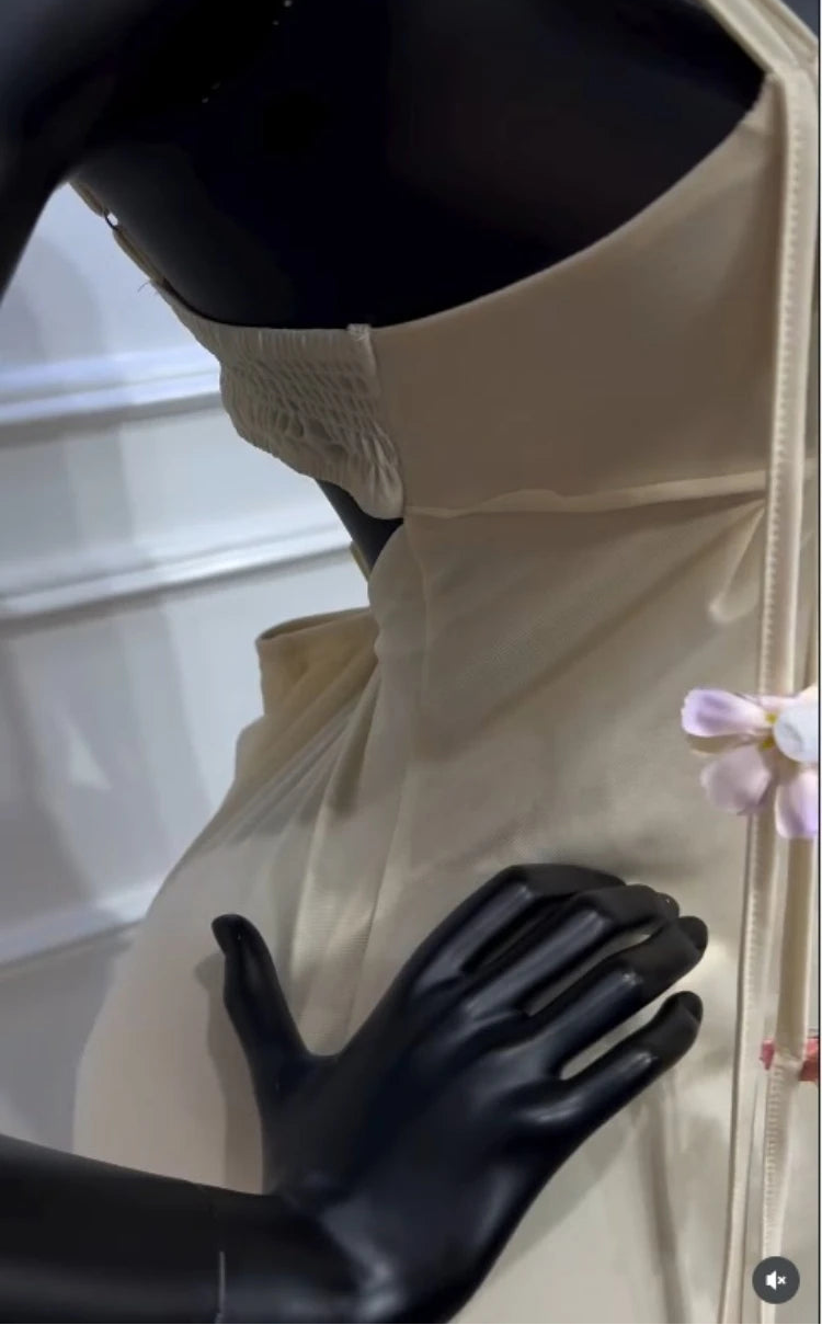 Mannequin wearing a white dress with black gloves in a display case.