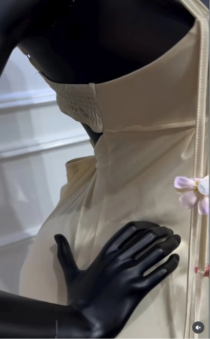 Mannequin wearing a white dress with black gloves in a display case.