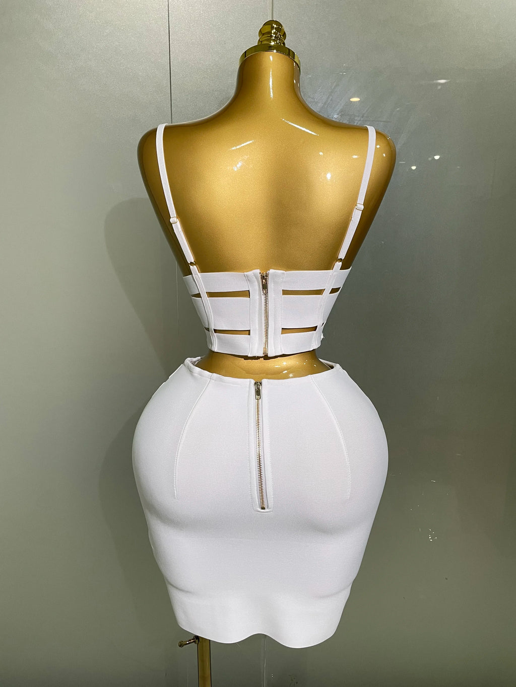 Sculpted bandage two piece set showcasing a white sculpted buckle crop top and fitted skirt from the back view.