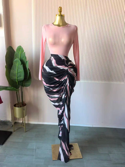 Alt Tag: Sculpted Mirage Draped Maxi Dress with pink fitted knit top, sculpted pleats, and abstract printed draped maxi skirt on mannequin