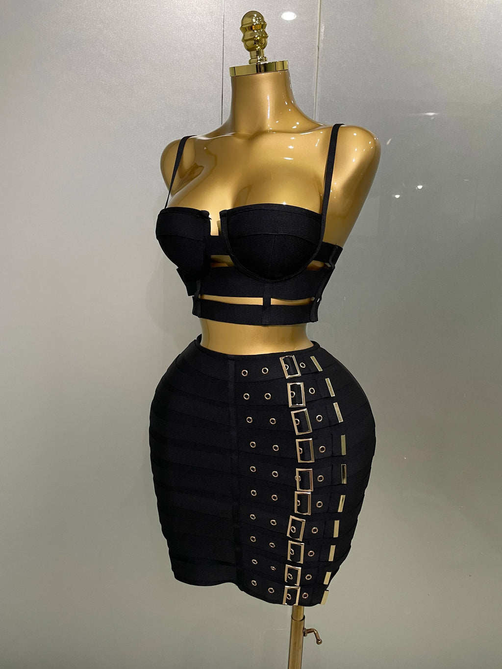 Alt Tag: Sculpted Buckle Bandage 2-Piece Set black bustier crop top and high-waist buckle bandage skirt on mannequin