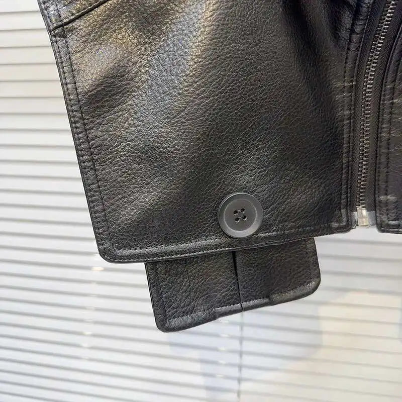 Close-up of the cuff detailing on a structured faux leather jacket featuring a button and textured fabric.